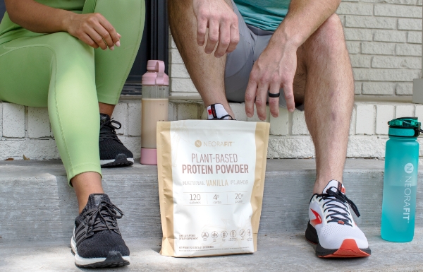 A man and woman resting outside with Plant-Based Protein Powder in front of them.