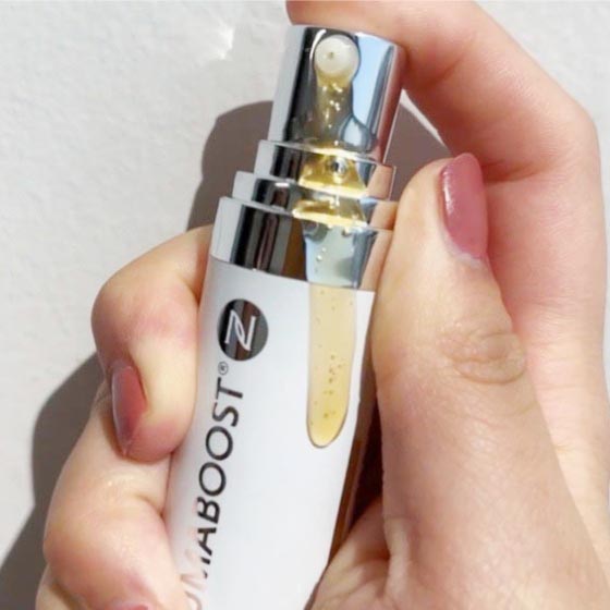Woman’s hand holding a bottle of Neora IllumaBoost Brightening Vitamin C Serum with partial contents spilling out of the bottle.